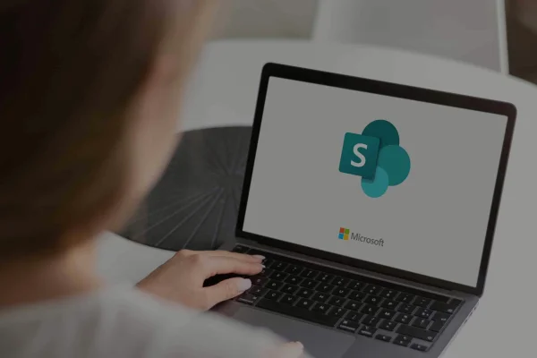 Laptop z logo SharePoint Online używany przez pracownika, promujący profesjonalne wdrożenie Microsoft 365 w firmie.