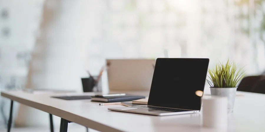 Otwarte laptopy na białym biurku w jasnym biurze, ilustrujące gotowość systemów firmy do audytu informatycznego.