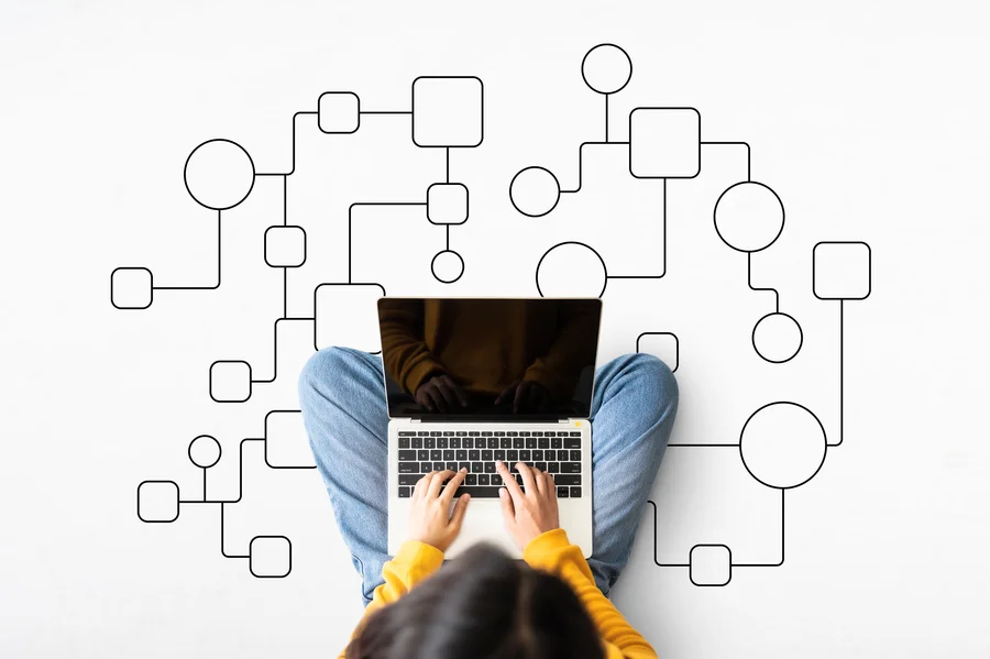 Osoba pracująca na laptopie, nad którą unosi się skomplikowany, logiczny schemat blokowy, symbolizujący procesy automatyzacji Microsoft Power Automate i Azure Functions.