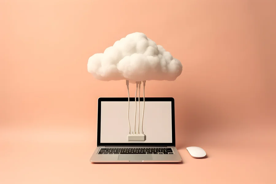 Laptop połączony przewodami z zawieszoną nad nim chmurą, symbolizujący bezpieczny proces tworzenia kopii zapasowej danych.