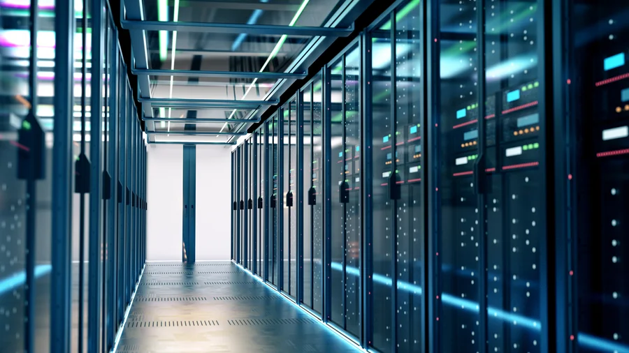 Widok na rzędy szaf serwerowych w nowoczesnym centrum danych z niebieskim oświetleniem LED. Profesjonalna infrastruktura IT zapewniająca bezpieczeństwo i ciągłość backupu danych.