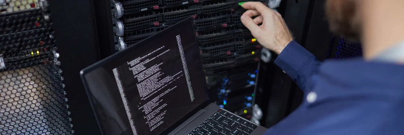 Inżynier systemowy Ebimedia konfigurujący parametry serwera na laptopie w profesjonalnej serwerowni.