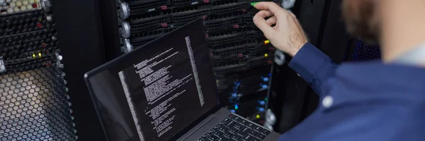 Inżynier systemowy Ebimedia konfigurujący parametry serwera na laptopie w profesjonalnej serwerowni.
