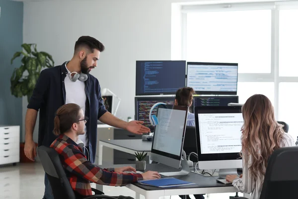 Specjaliści IT podczas wspólnej pracy nad kodem i architekturą systemów w nowoczesnym biurze.